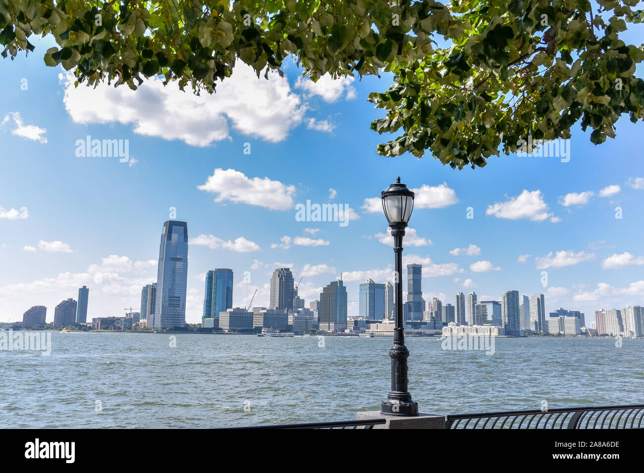 New Jersey Skyline vom Battery Park an einem sonnigen Tag. Stadtbild Blick durch Bäume und Laterne. Stadt und Travel Concept. Manhattan, New York City, U Stockfoto