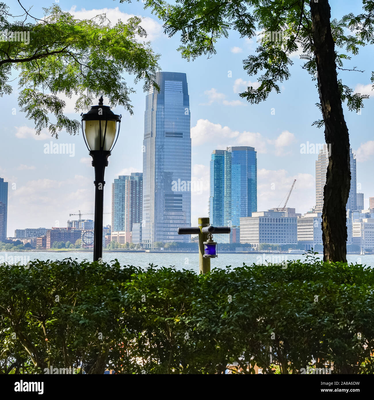 New Jersey Skyline vom Battery Park an einem sonnigen Tag. Stadtbild Blick durch Bäume und Laterne. Stadt und Travel Concept. Manhattan, New York City, U Stockfoto