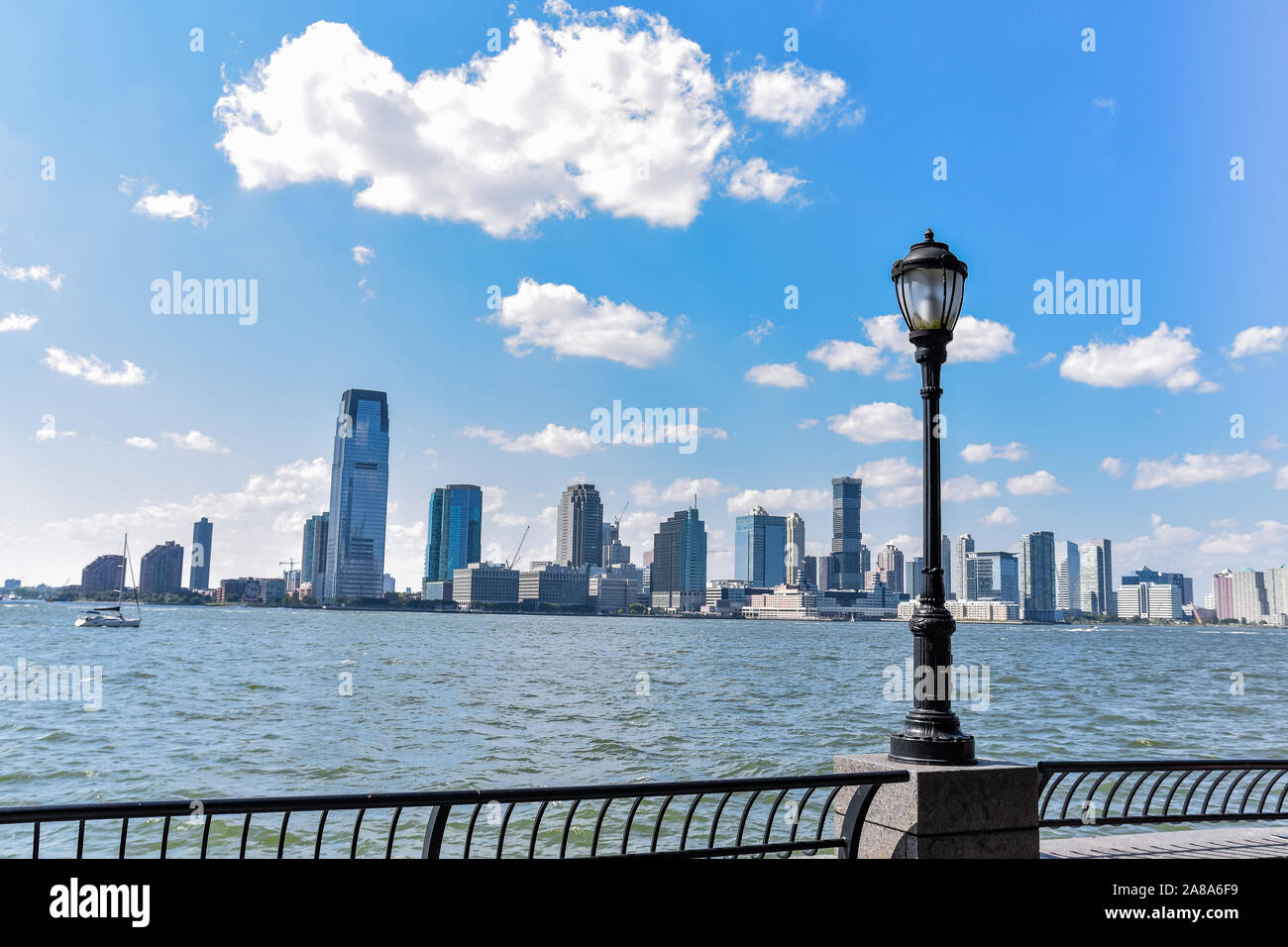 New Jersey Skyline vom Battery Park an einem sonnigen Tag. Stadtbild Blick durch Bäume und Laterne. Stadt und Travel Concept. Manhattan, New York City, U Stockfoto