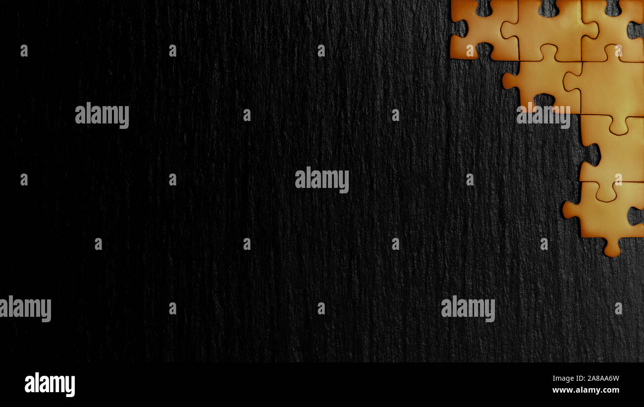 Orange Puzzle in der Ecke des Bildes auf einem schwarzen Hintergrund der Naturstein Schiefer. Ein Frame mit einem leeren Raum für ihre Beschreibung. Stockfoto