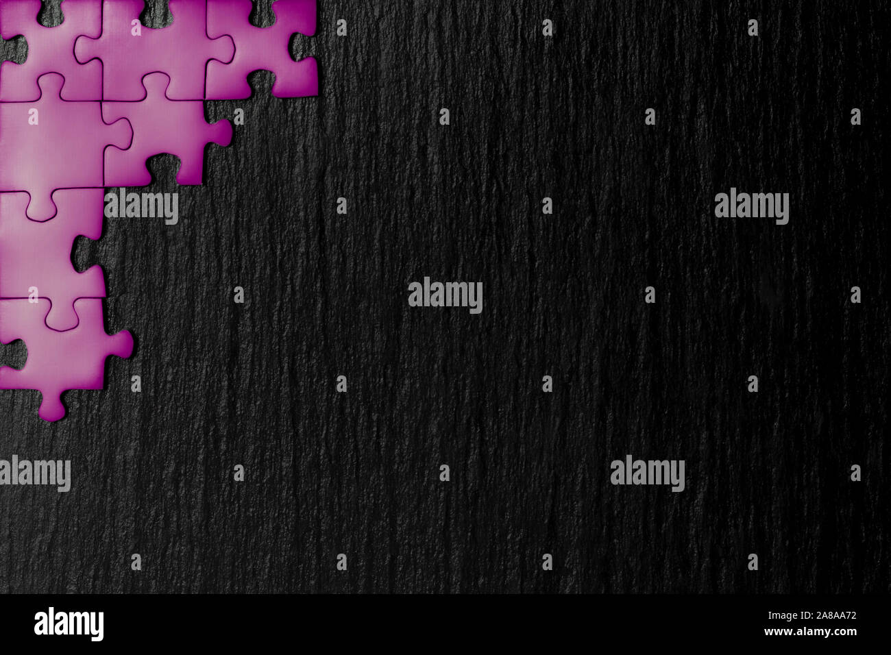 Purple Puzzle in der Ecke des Bildes auf einem schwarzen Hintergrund der Naturstein Schiefer. Ein Frame mit einem leeren Raum für ihre Beschreibung. Stockfoto