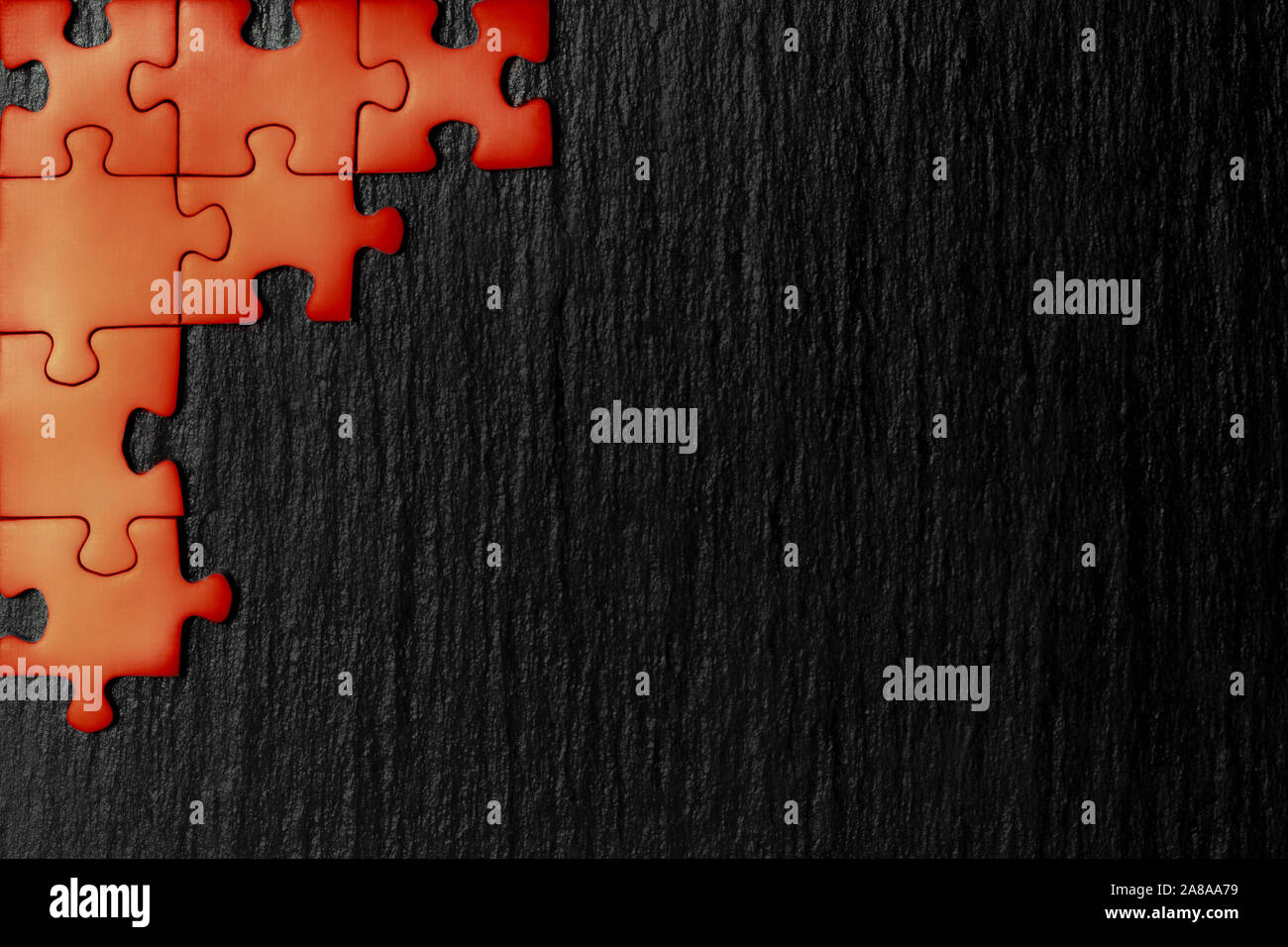 Red Puzzle in der Ecke des Bildes auf einem schwarzen Hintergrund der Naturstein Schiefer. Ein Frame mit einem leeren Raum für ihre Beschreibung. Stockfoto