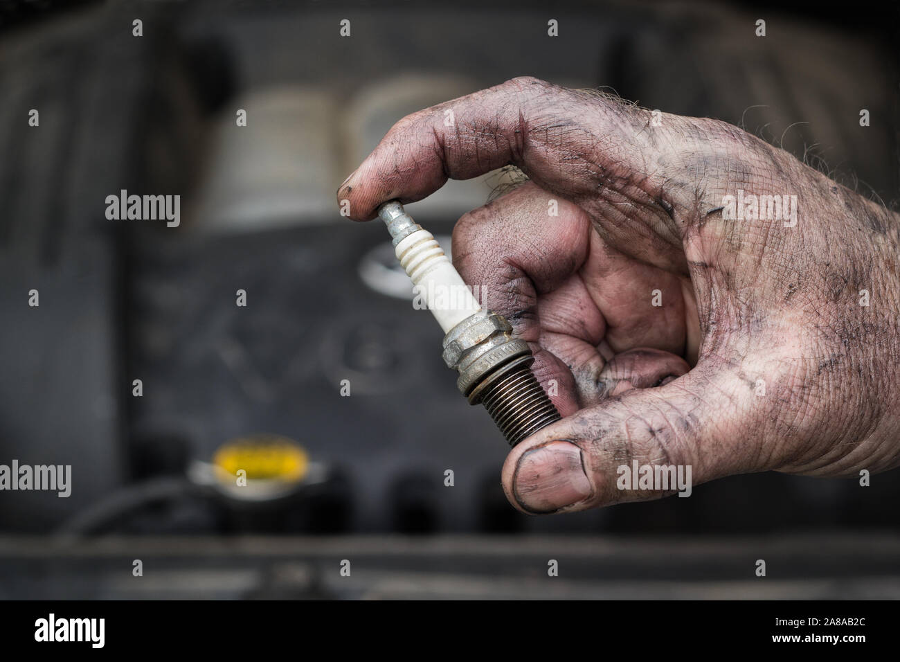 Automechaniker holding Stopfen vor dem Fahrzeug Motor Funken. Stockfoto