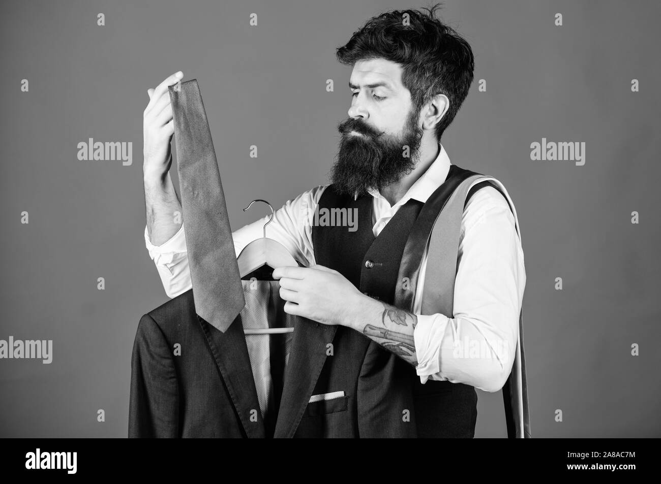 An der mens Boutique. Hipster passende Krawatte zu mens Anzug Jacke. Unternehmer, die formalen mens Zubehör Auswahl im Schrank. Bärtiger Mann Auswahl mens Krawatten an den Abteilung Speichern. Stockfoto