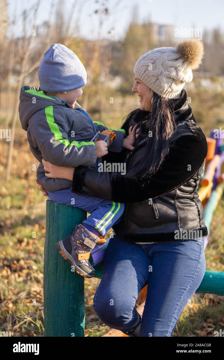 Mutter - ein im mittleren Alter Junge brünette Frau spielt mit ihrem dreijährigen Sohn an einem sonnigen Herbsttag. Fröhliche Stimmung, lächeln Stockfoto