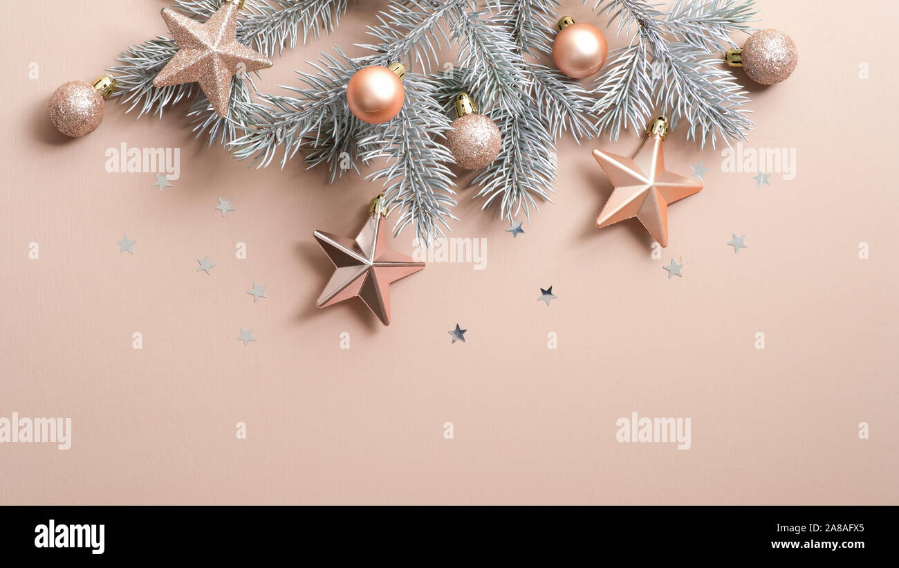 Ansicht von oben Weihnachtsbaum Zweig mit Kupfer Farbe Sterne und Kugeln über beigen Hintergrund mit Glitzer Konfetti. Xmas minimal flach Stil Zusammensetzung, Stockfoto