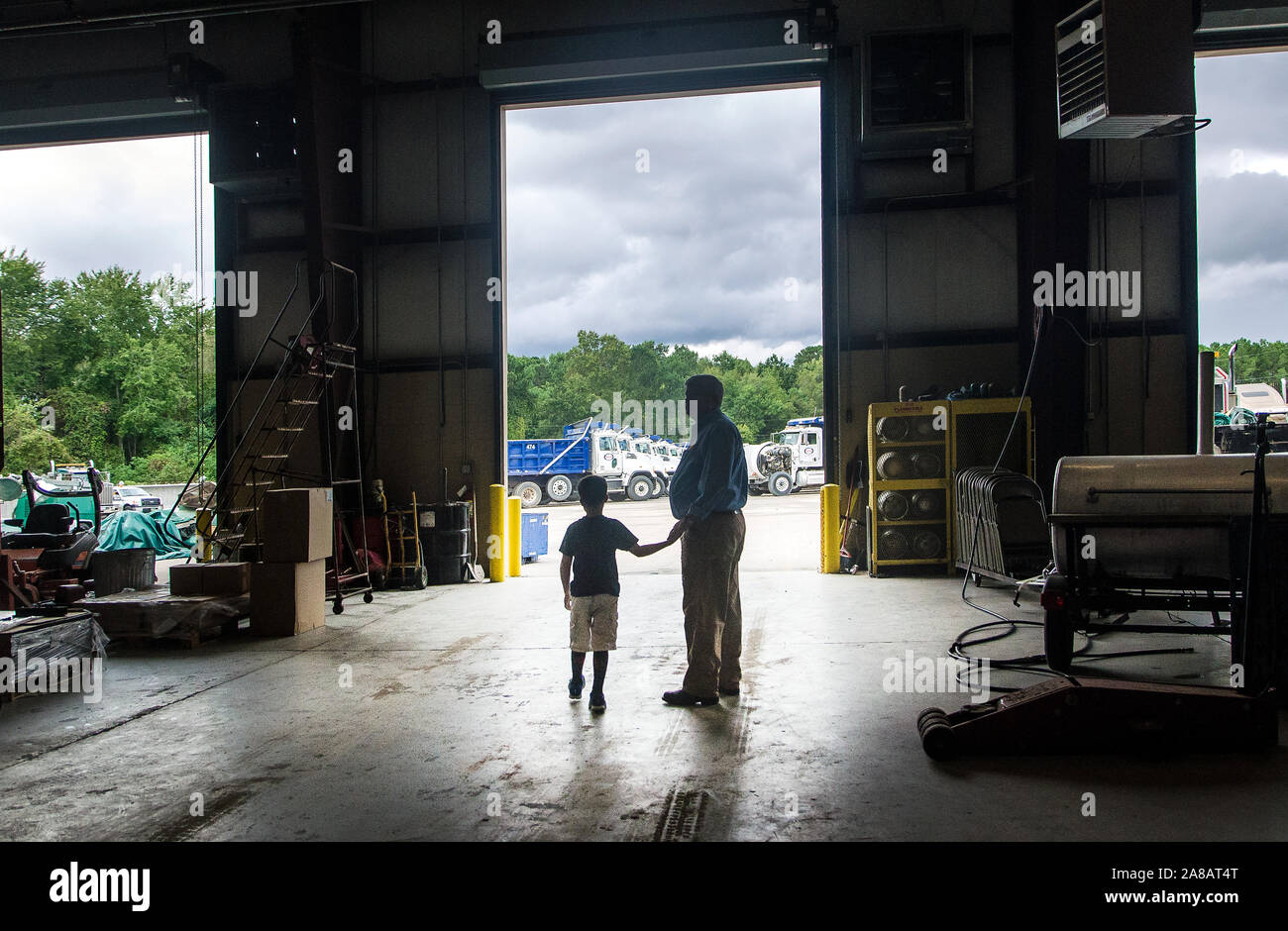 Ein Mann und sein Sohn sind Silhouette, wie sie der Instandhaltungswerkstatt im Superior Transport, Sept. 30, 2015 verlassen, in North Charleston, South Carolina. Stockfoto