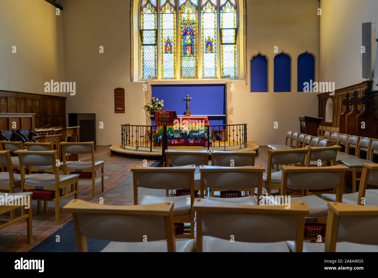 Der Altar der Anglikanischen Kirche mit einem Glasfenster hinter von Stühlen umgeben Stockfoto