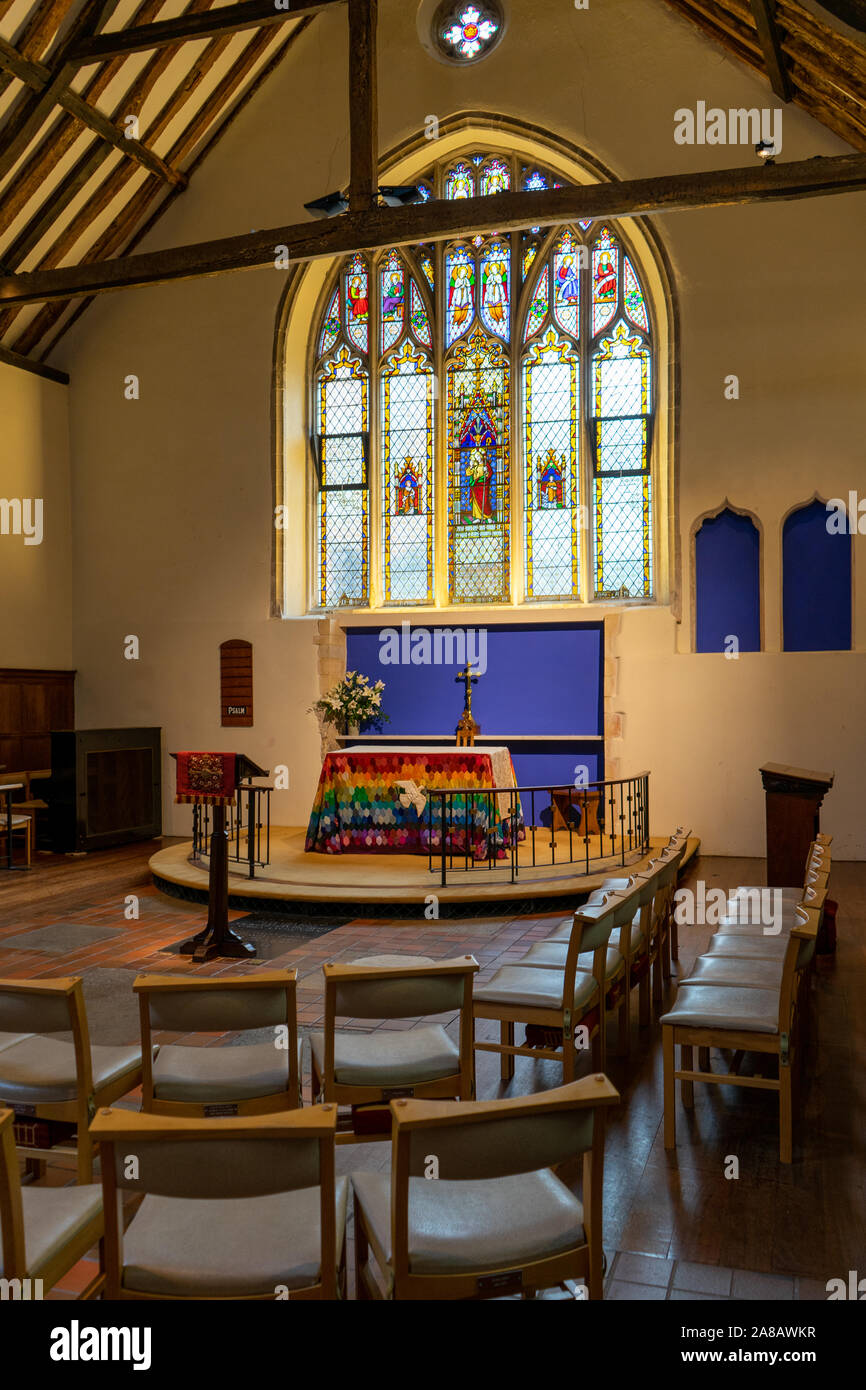 Der Altar der Anglikanischen Kirche mit einem Glasfenster hinter von Stühlen umgeben Stockfoto