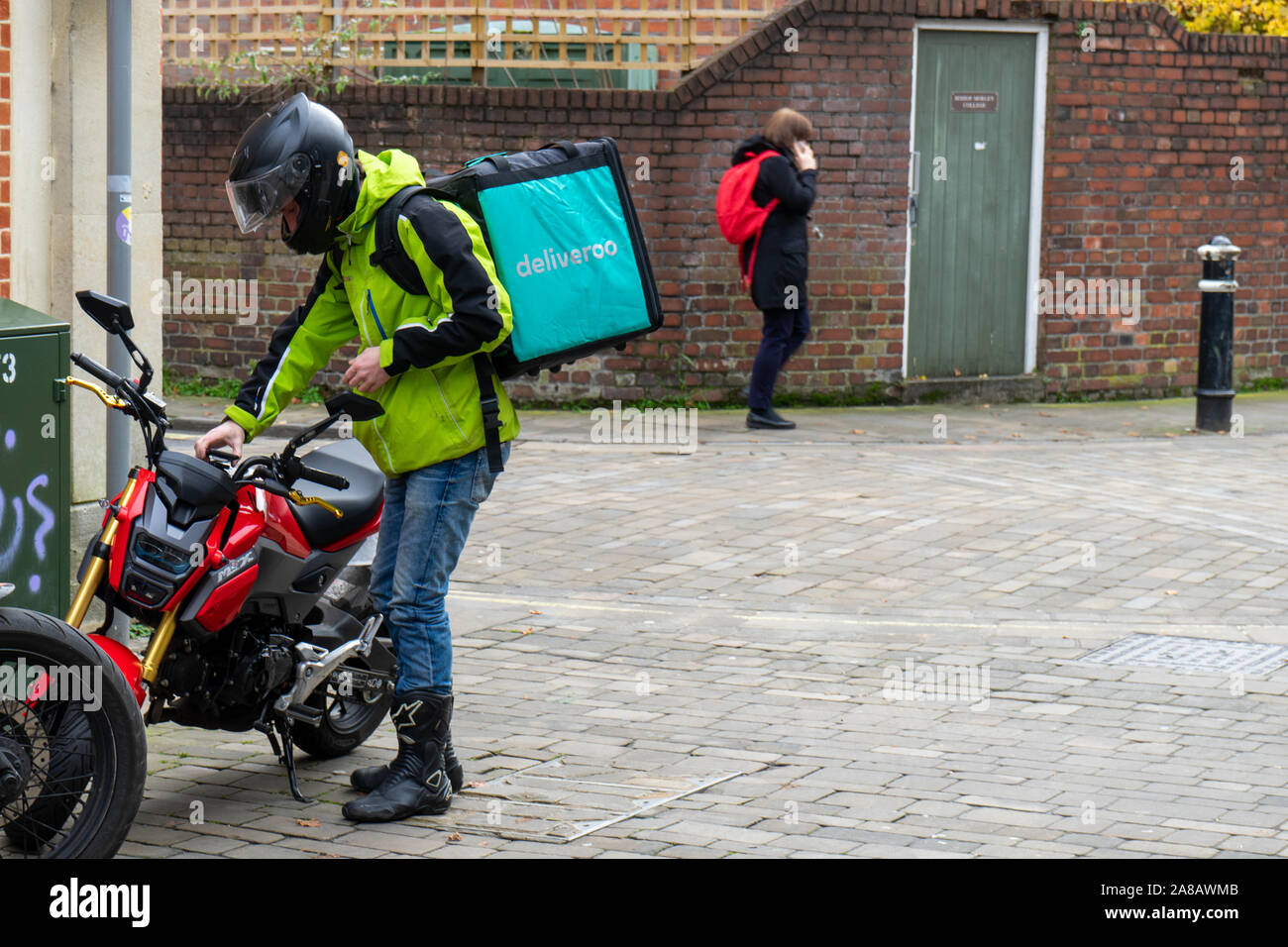 Eine deliveroo Fahrradfahrerin auf seinem Motorrad mit einem deliveroo Tasche auf dem Rücken Stockfoto