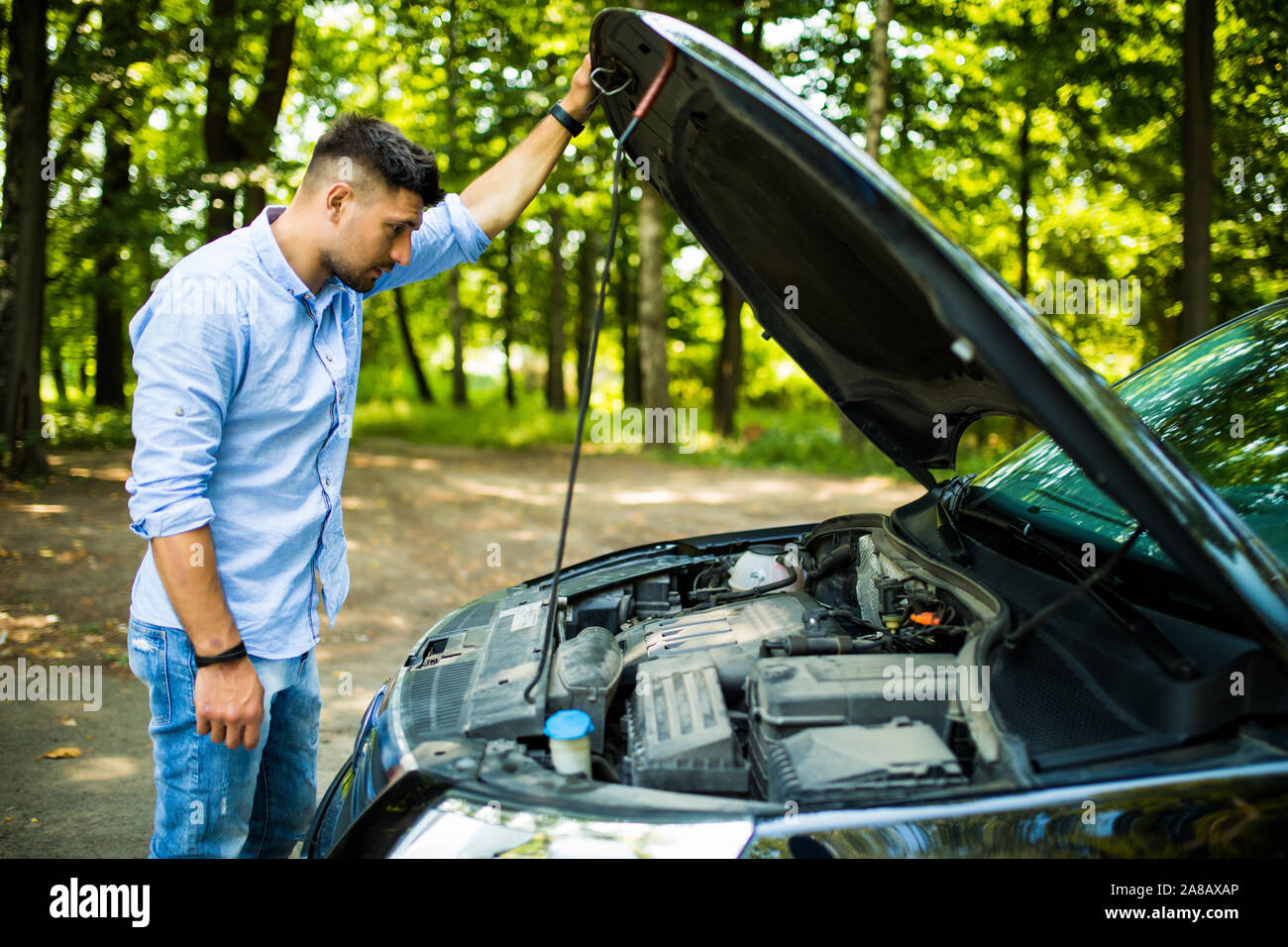 Junger Mann auf der Straße in Problem mit einem Auto. Schlüsselt man die Autos auf der Straße. Reisen problem. Stockfoto