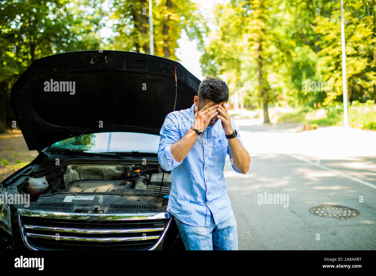 Junger Mann auf der Straße in Problem mit einem Auto. Schlüsselt man die Autos auf der Straße. Reisen problem. Stockfoto