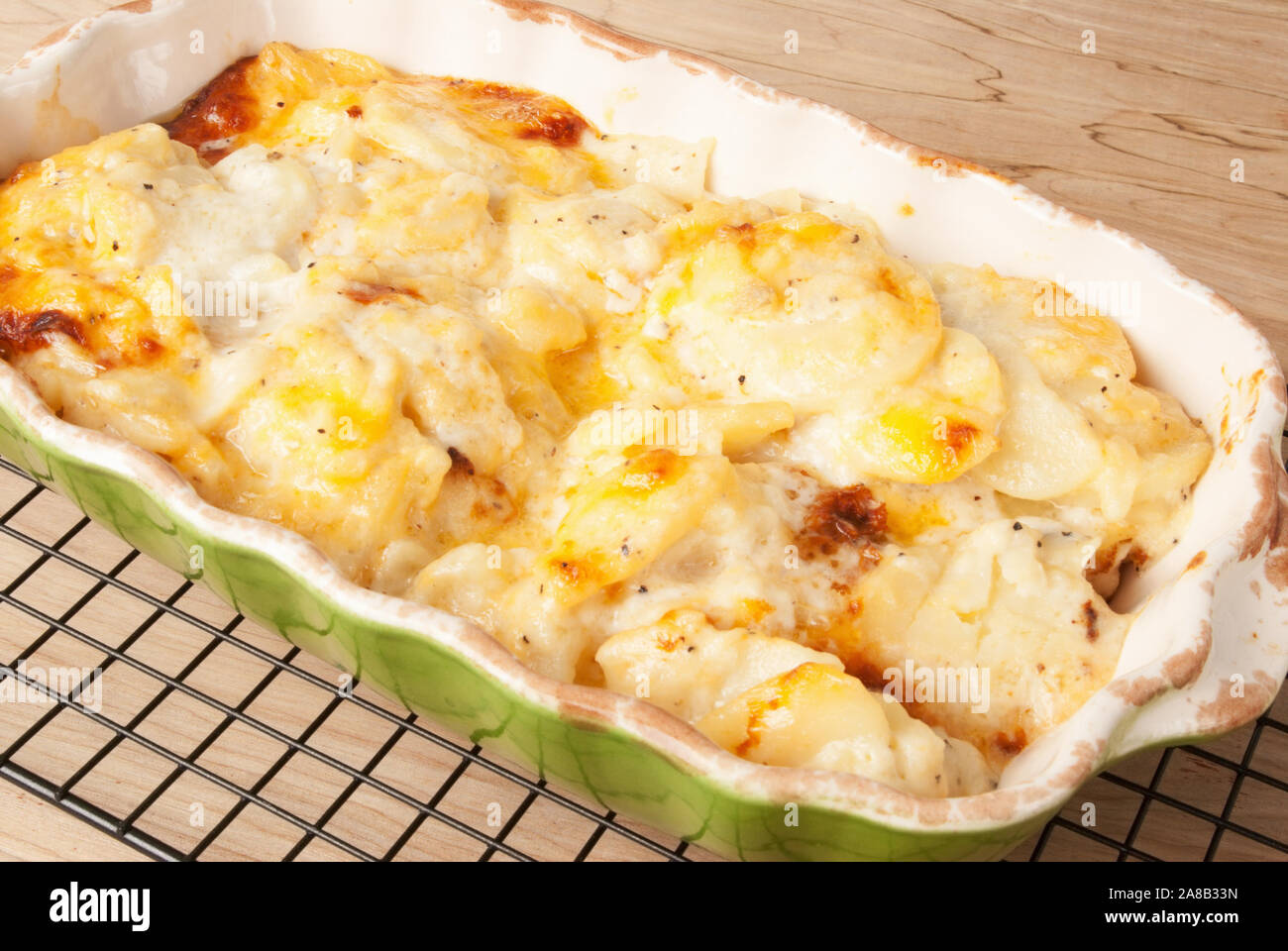 Hausgemachte gebackene überbackene Kartoffeln mit Golden Brown Cheddar Käse. Heiß aus dem Ofen auf einem Gitter. Natürliches Licht von der Rückseite. Selecti Stockfoto