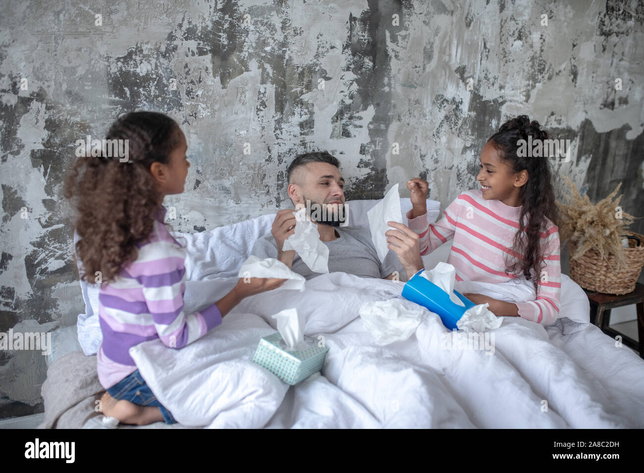 Zwillinge die Pflege von Papa im Bett blieben nach dem Fang kalt Stockfoto