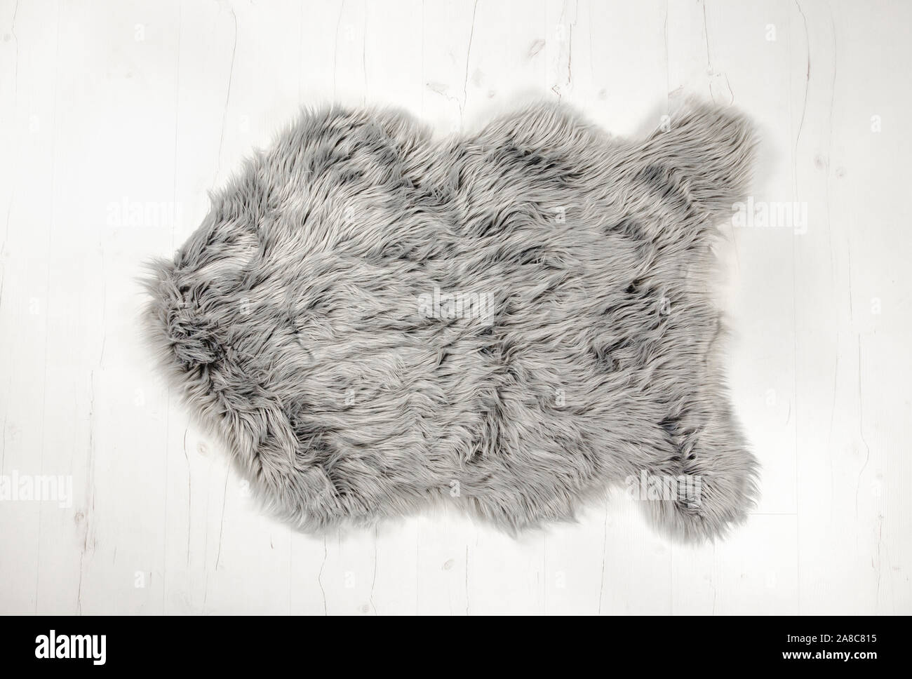 Flach legen Blick auf grau warm und gemütlich ganze dekorative gefälschte Schaffell Form Teppich auf weißem Holzbrett Boden. Kopierraum, Studio-Set. Stockfoto