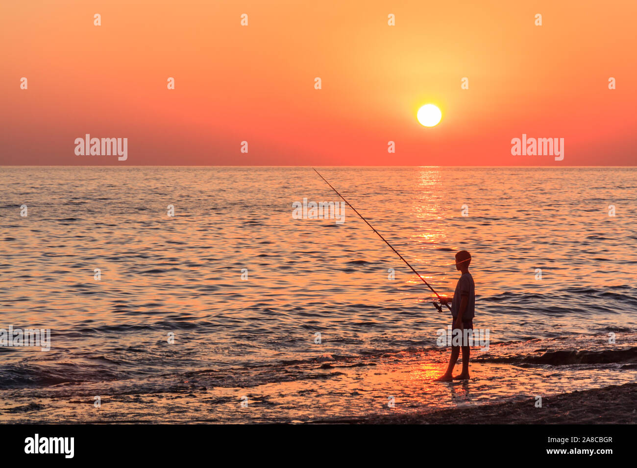 Silhouette von jungen Fischen bei Sonnenuntergang in Alanya, in der Türkei Stockfoto