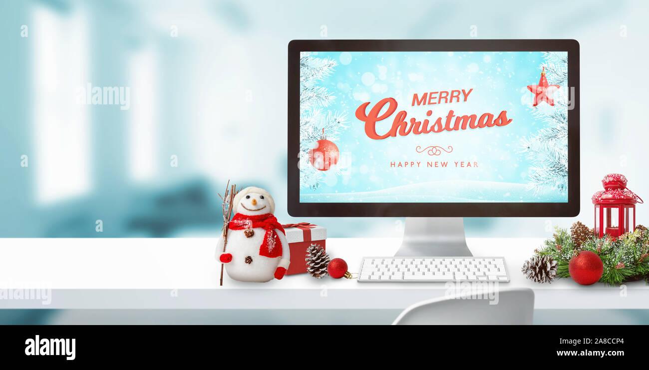 Mery Christmas auf dem Computer anzeigen und Dekorationen auf Schreibtisch. Kopieren Sie Platz neben. Computer Display mockup. Stockfoto