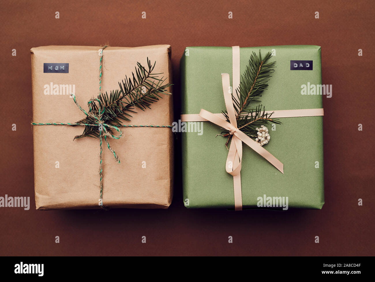 In der Nähe von zwei Weihnachten Geschenkboxen dekoriert Tannenzweigen auf braunem Hintergrund isoliert Stockfoto