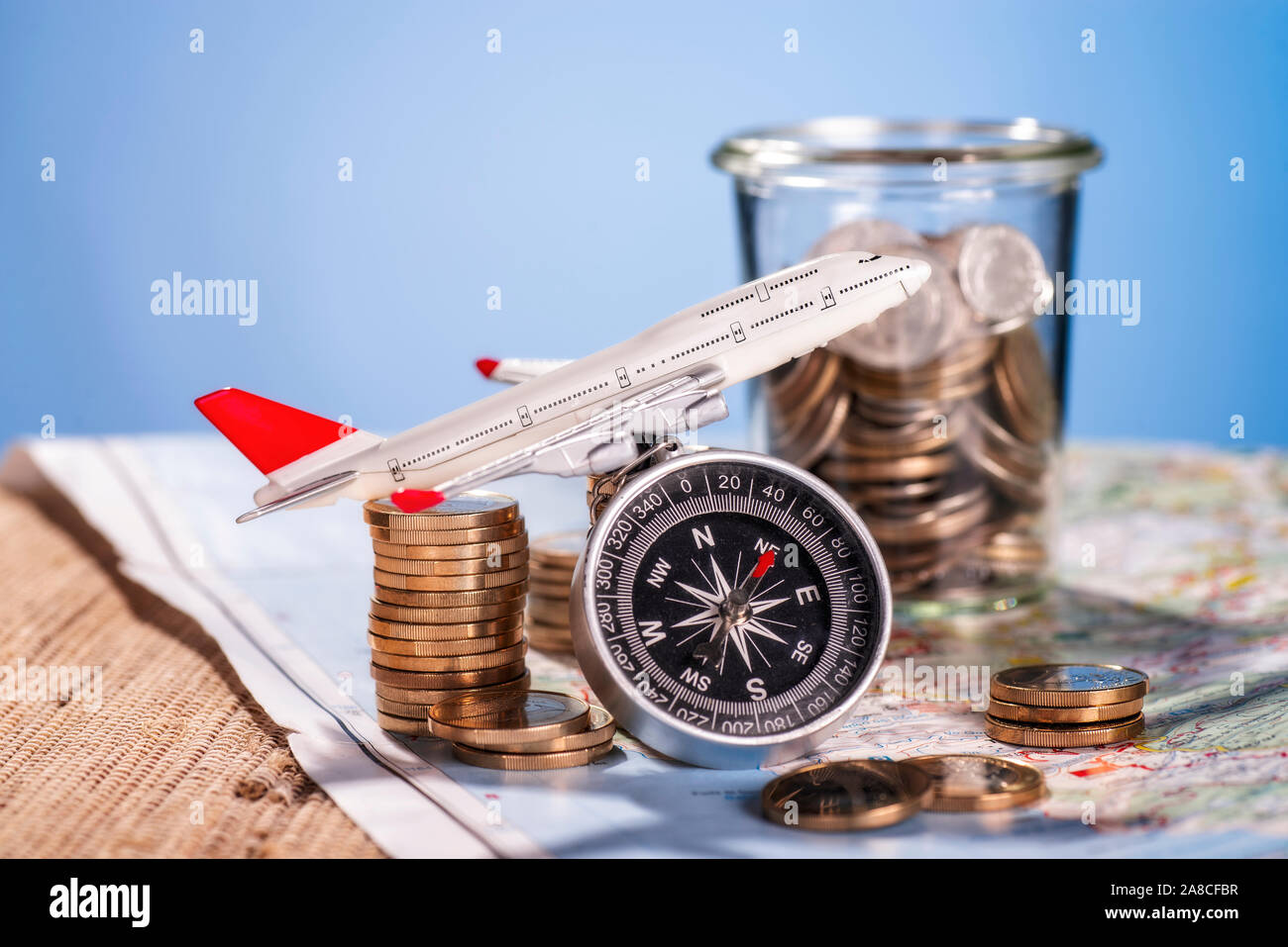 Flugzeug mit Kompass und Münzen auf einer Karte Stockfoto