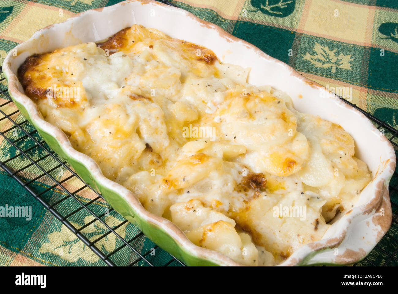 Hausgemachte gebackene überbackene Kartoffeln überbacken garniert mit Golden Brown Cheddar Käse. Heiß und direkt aus dem Ofen. Der Hintergrund ist eine Danksagung t Stockfoto