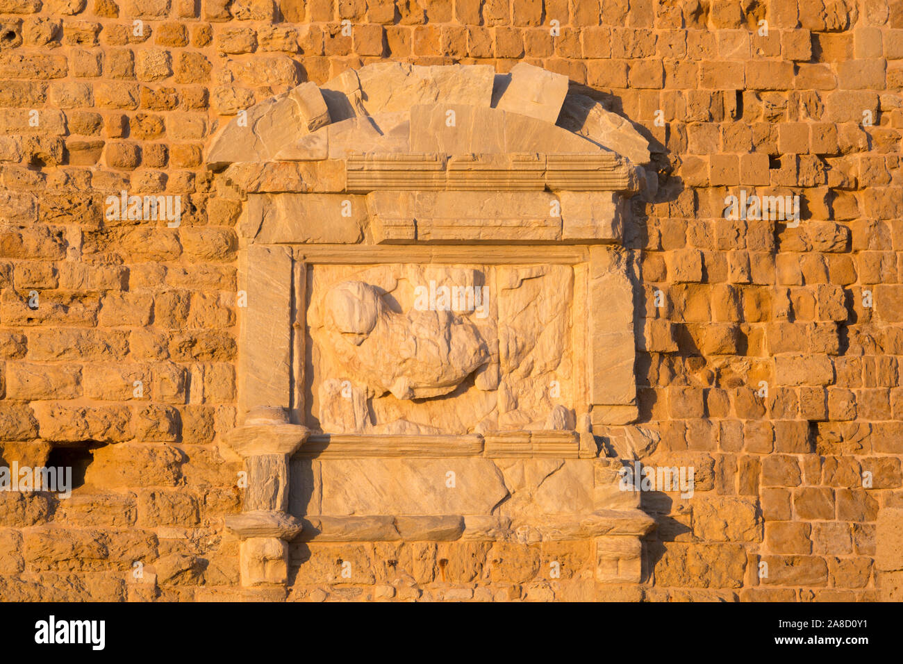 Heraklion, Kreta, Griechenland. Schlecht erodiertes Marmorrelief des Löwen von St. Mark an der Wand der Festung Koules, Sonnenuntergang. Stockfoto