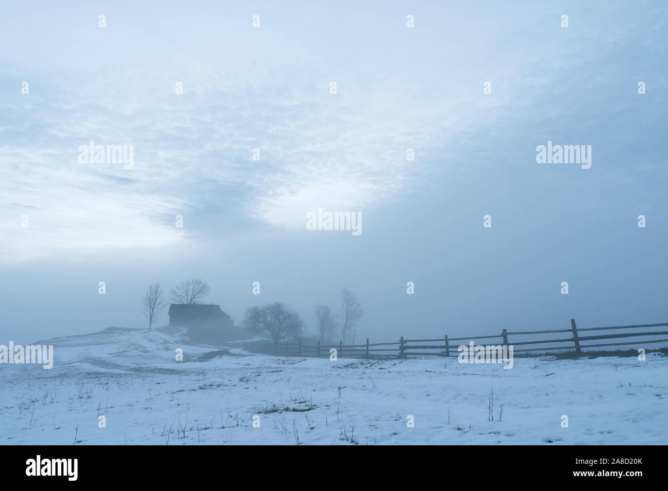 Landschaft mit einem Haus auf einem Hügel im Dorf. Winter morgen mit einem Nebel Stockfoto