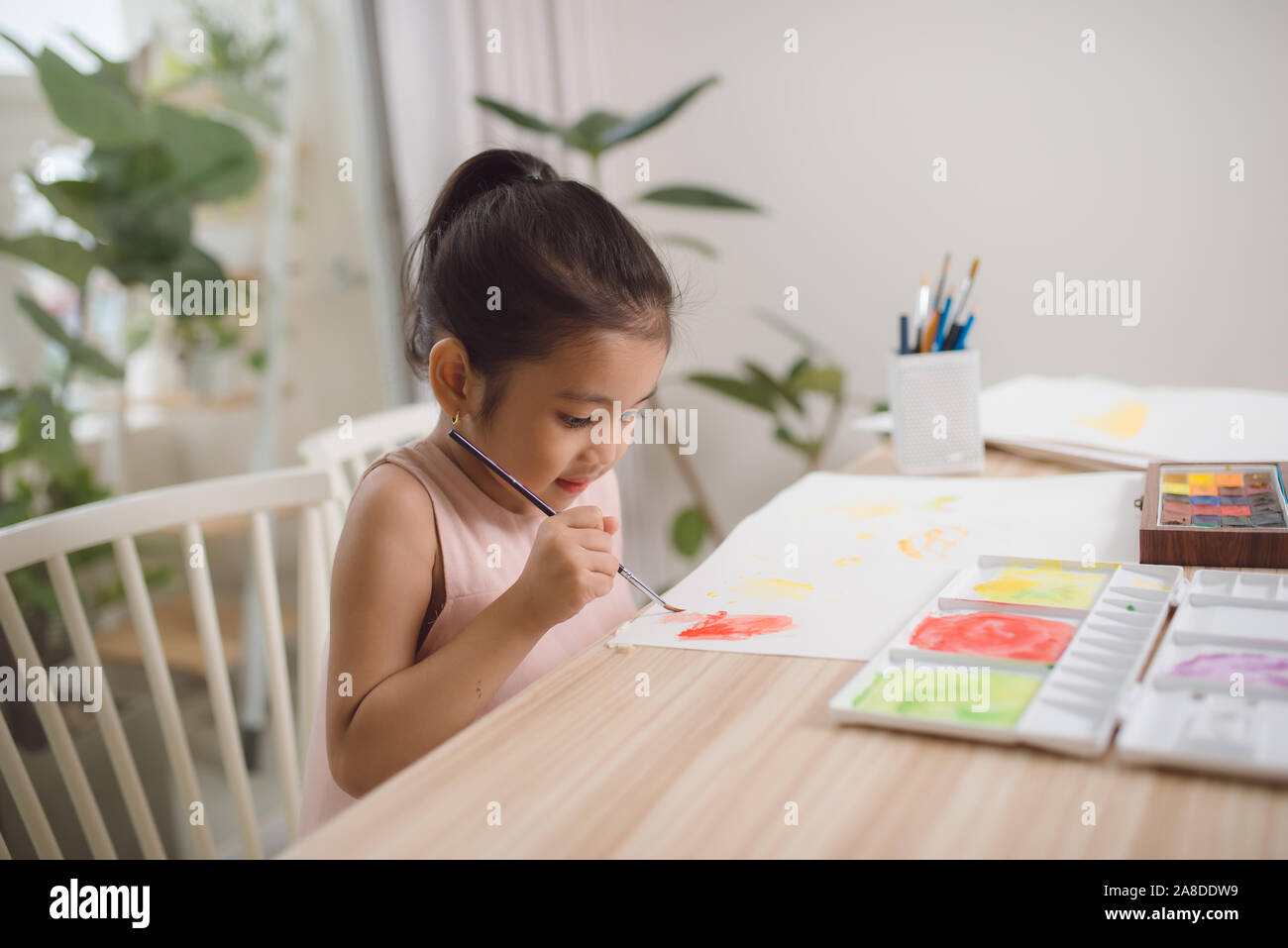 Süße kleine asiatische Mädchen genießen die Malerei zu Hause mit Papier, Wasser Farbe und Pinsel. Stockfoto