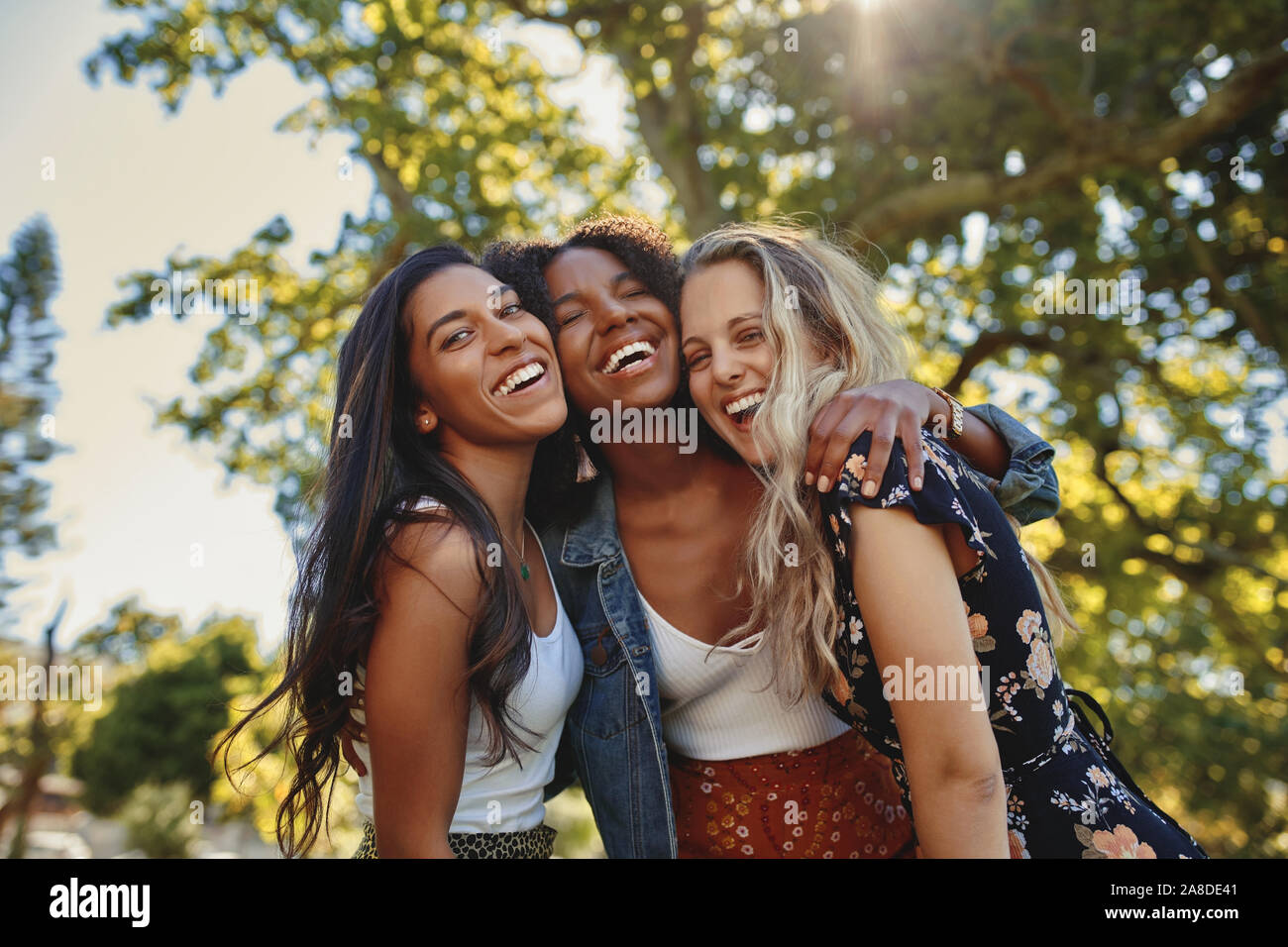 Portrait Of Happy multiethnische Gruppe von lächelnd weibliche Freunde - Frauen lachen und Spaß im Park an einem sonnigen Tag Stockfoto