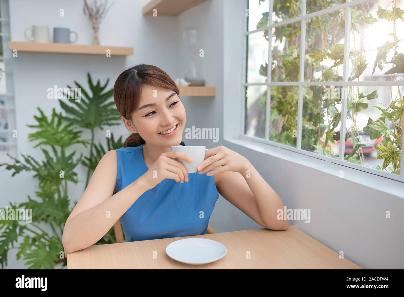 Portrait von jungen asiatischen Mädchen genießen Frühstück Kaffee hinter dem Fenster Stockfoto