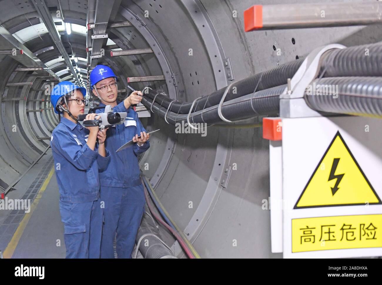 Chinesische Arbeiter aus der lokalen Stromversorgung Präsidium Patrol und 220 kv-höchstspannungsleitung Stromkabel unterirdisch in Foshan City, South China' befestigt prüfen Stockfoto