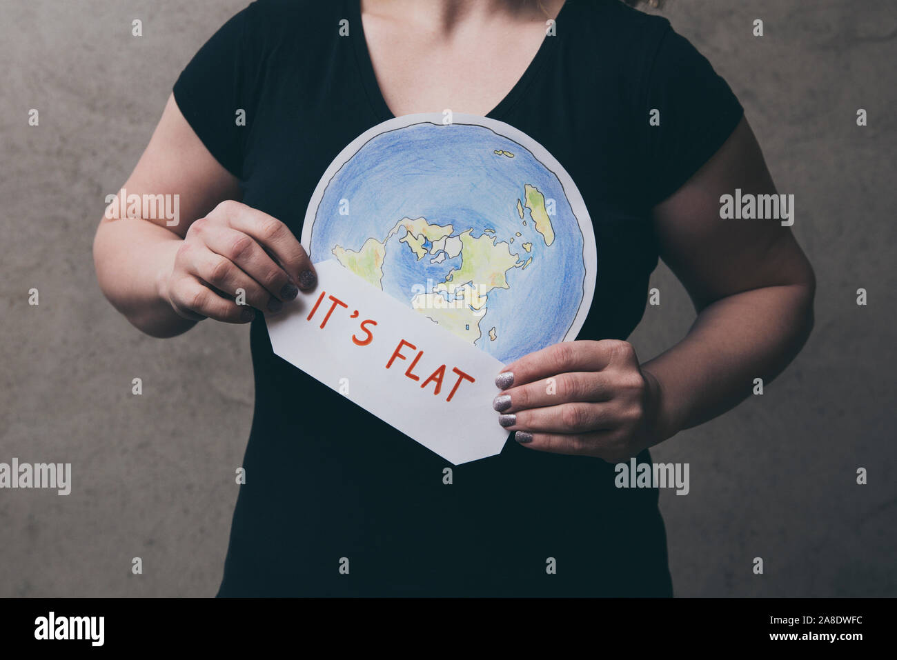 Flache Earther Konzept. Person, die glaubt, dass die Erde flach ist. Anonyme Frau mit flachen Erde Modell vor der Körper mit Text: Es ist flach. Iso Stockfoto