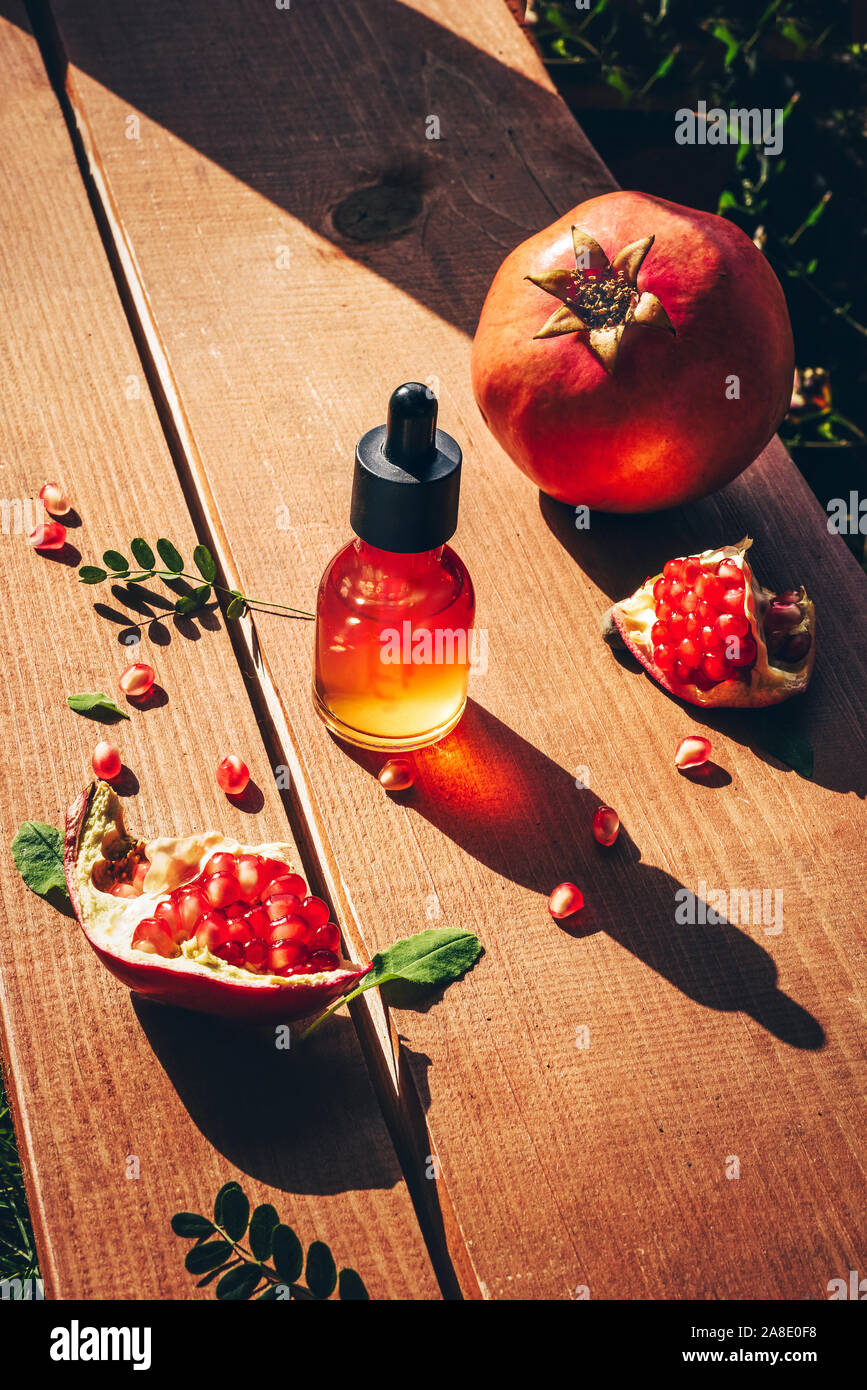 Granatapfel Kernöl, Serum in Flasche auf Holz- Hintergrund. Lifestyle Konzept Anti-Aging-Hautpflege Stockfoto