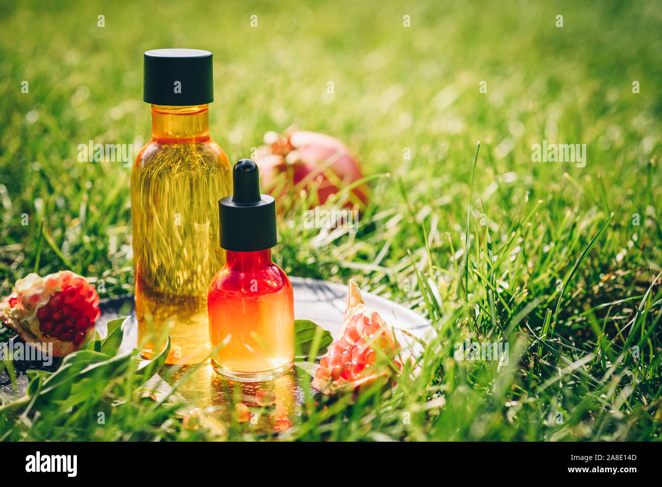 Granatapfel Kernöl, Serum in unterschiedlichen Flaschen grünes Gras Konzept der Anti-aging Organic Skin Care Stockfoto