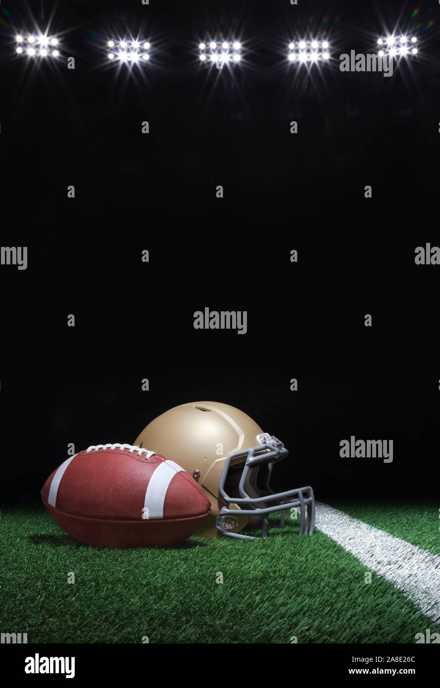 Fußball und gold Helm auf Gras Feld unten Stadion Lichter in der Nacht Stockfoto