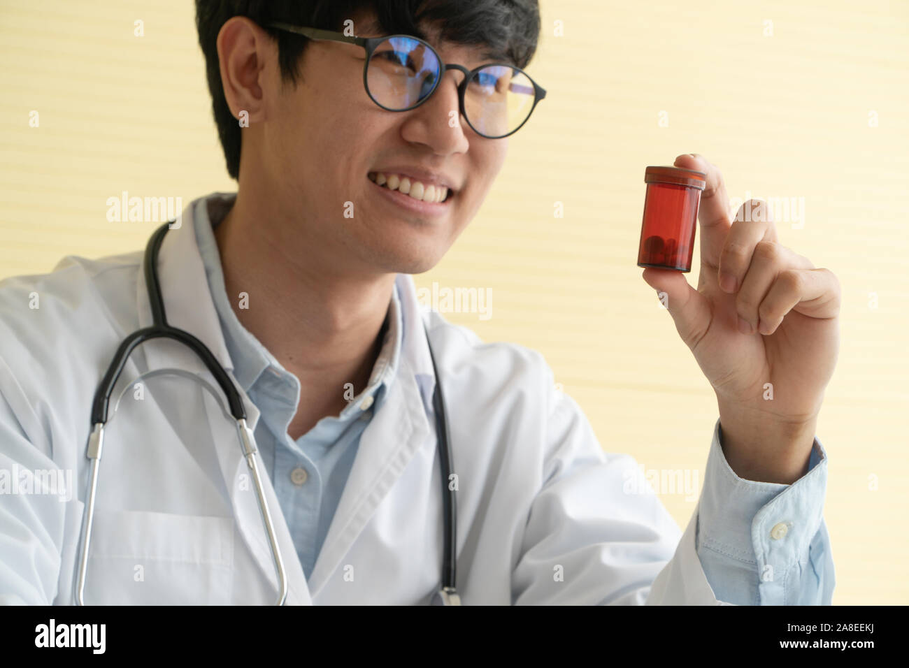 Asiatische Arzt mit Stethoskop und einheitliche Holding eine Medizin Flasche und erklärt die medizinischen Eigenschaften des Patienten. Konzept der Medizinischen con Stockfoto