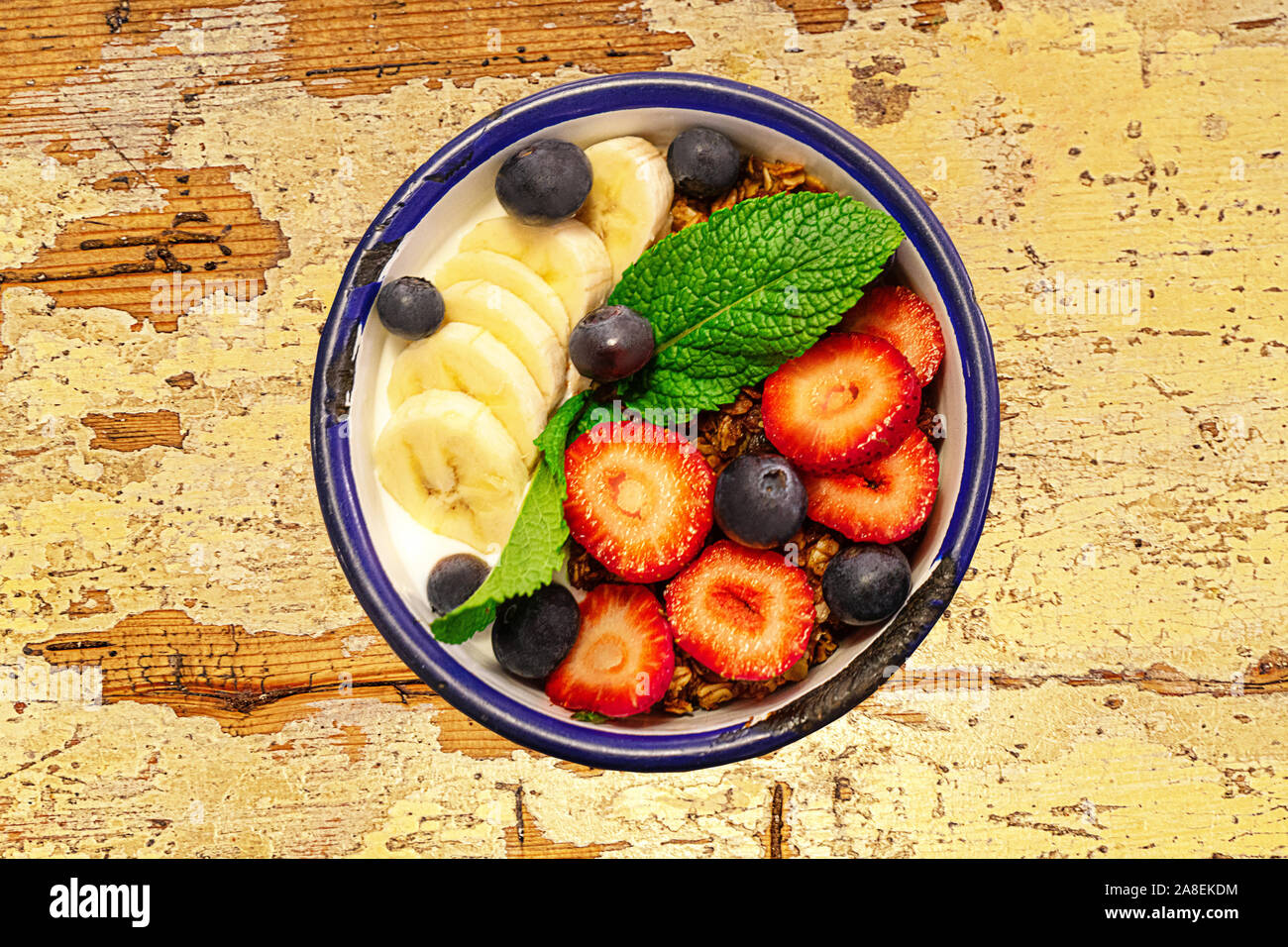 Schüssel mit Müsli und Obst, grüne Minze Blatt auf alten Holztisch. Nahaufnahme, Ansicht von oben, flach. Selektive konzentrieren. Stockfoto
