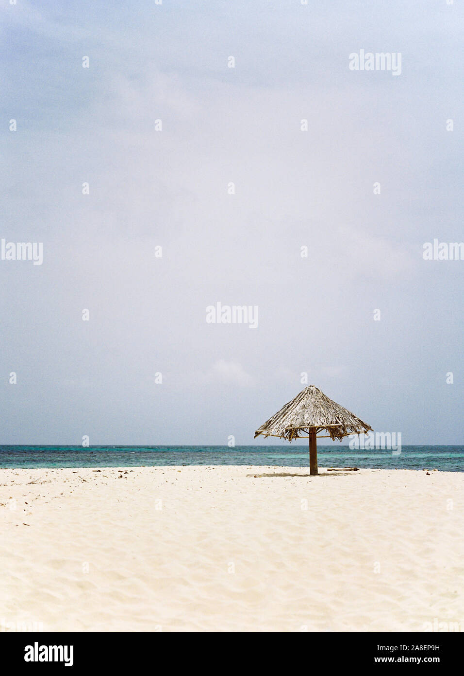 Eine Palme Wedel Dach ruht auf dem isolierten Insel Strand von Mopion in St. Vincent und die Grenadinen. Stockfoto