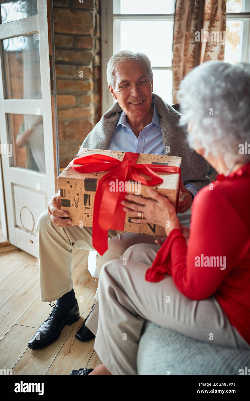 Happy Family open präsentiert auf Weihnachten Morgen. Lächelnd älterer Mann und Frau ihre Weihnachtsgeschenke austauschen Stockfoto