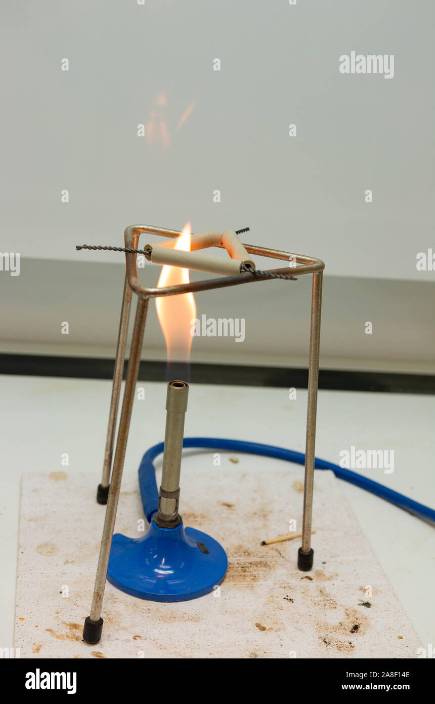 Bunsenbrenner mit Stativ und Leitung Ton Dreieck in einem Labor workbench in Großbritannien, beleuchtet mit einer Flamme Stockfoto