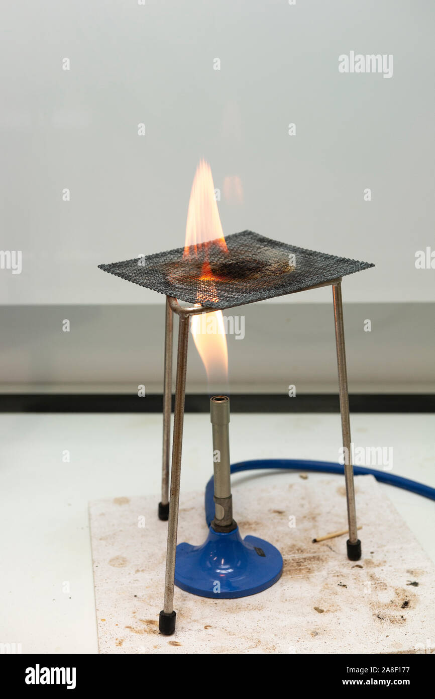 Bunsenbrenner mit Stativ und Gaze in einem Labor workbench in Großbritannien mit einer Flamme Stockfoto