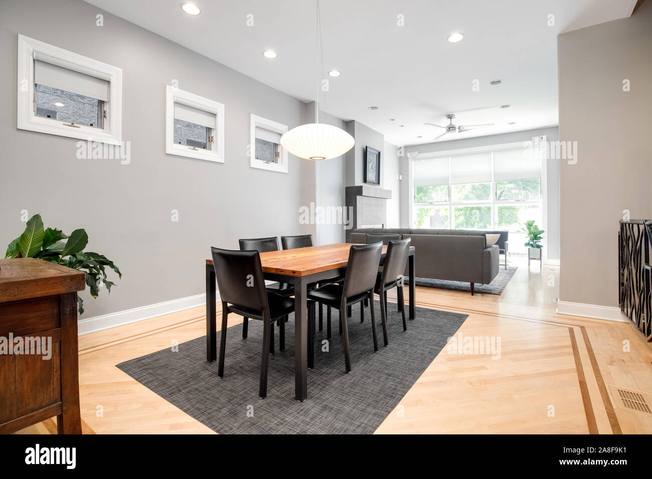Ein luxuriöser Speisesaal, der mit dem Wohnzimmer verbunden ist. Dieses geräumige Bereich kann ein großer Tisch mit einem modernen Licht nach unten hängen über der Oberseite anbringen. Stockfoto
