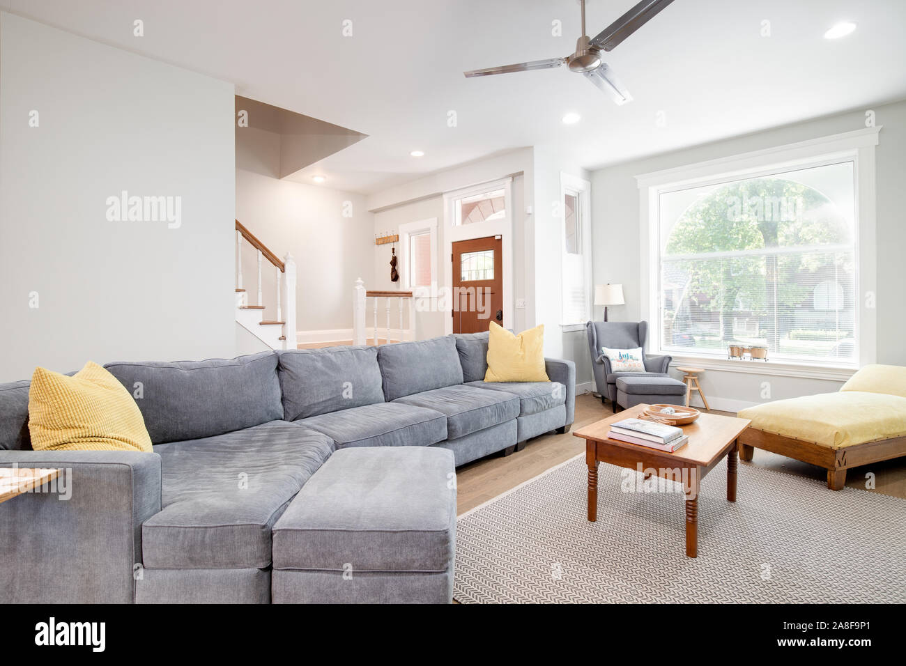 Ein luxuriöses Wohnzimmer in einem Viertel in der Innenstadt von Chicago. Das Zimmer verfügt über einen großen, grauen Couch mit gelben Akzent Kissen und eine Decke. Stockfoto