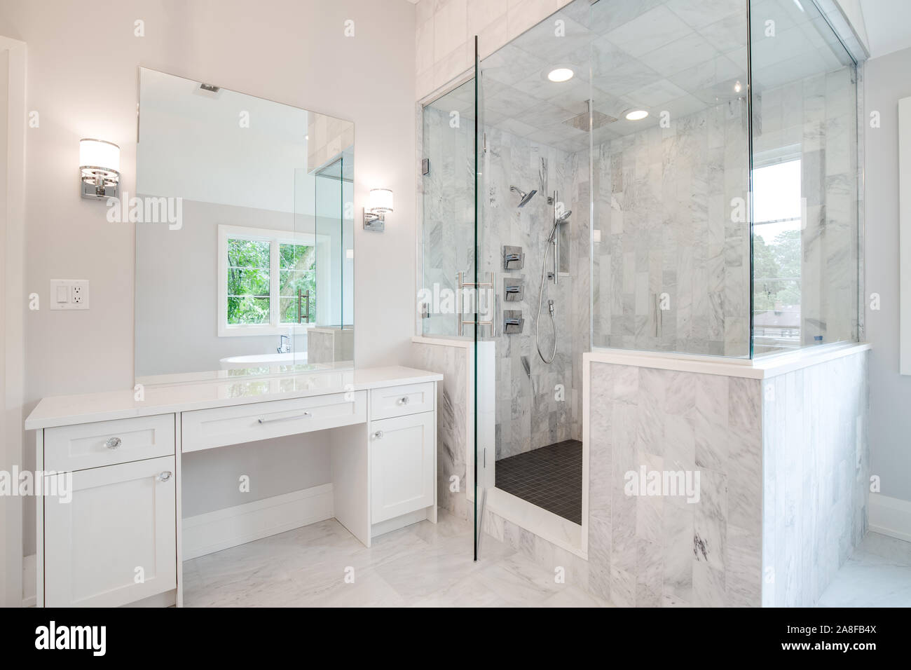 Ein helles Luxus Badezimmer mit einer großen Dusche und kleine, weiße  Eitelkeit Zähler nach oben. Ein Stand-alone-Wanne kann durch den Spiegel  gesehen werden Stockfotografie - Alamy