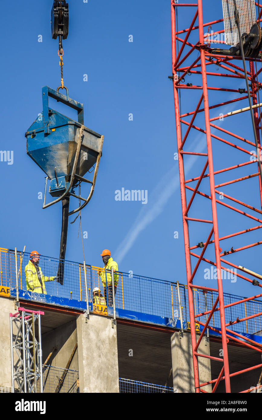 Handwerker stehen auf dem Dach eines riesigen Hochhauses Hilton Hotel Entwicklung als Kranführer, Treiber neue Teile des Gebäudes entlädt, Struktur Stockfoto