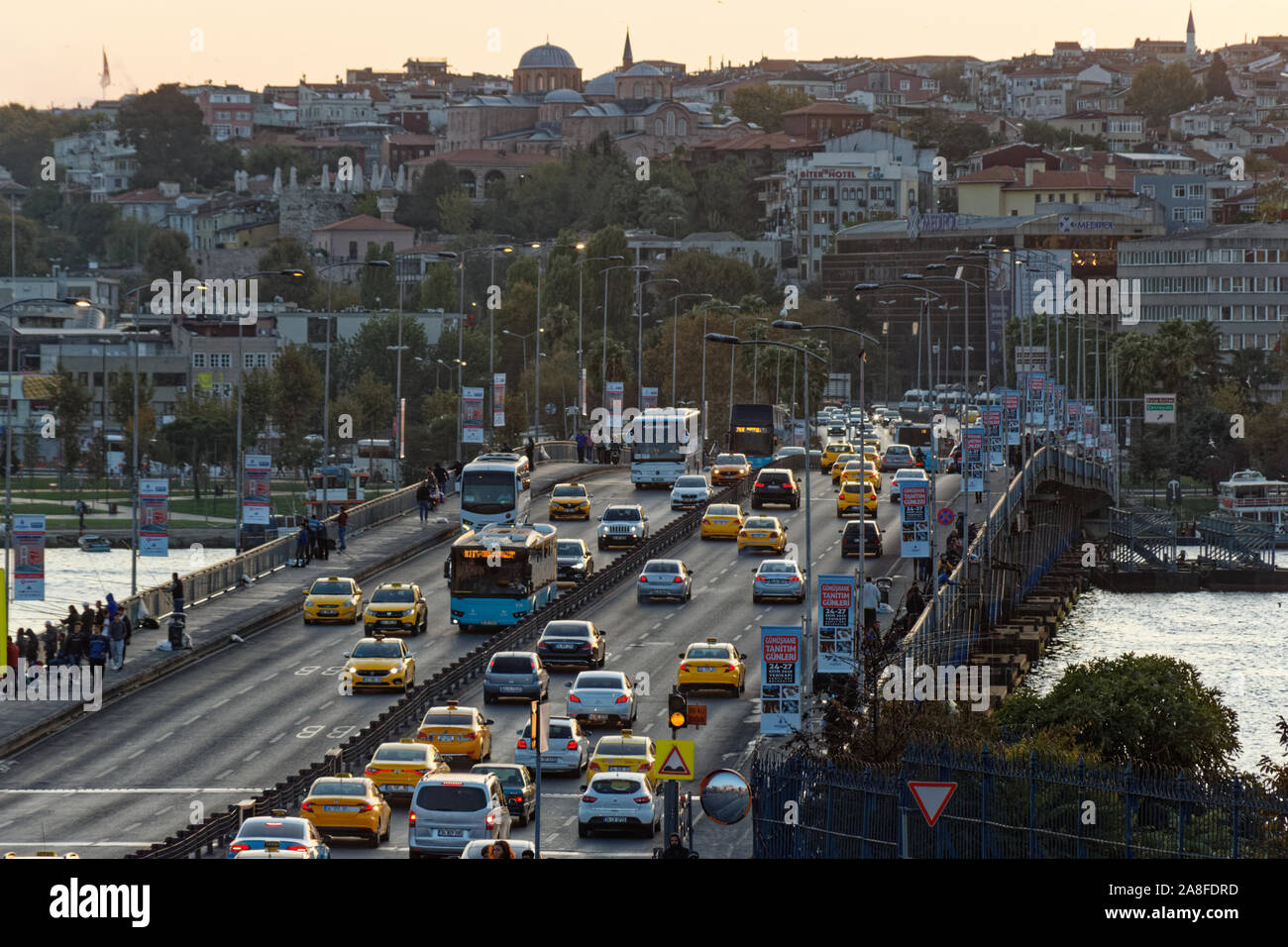 Fahrzeuge fahren durch Unkapani Brücke bei Sonnenuntergang Stunde. Front- und Rückansicht des Taxis, Autos und Busse. Stockfoto
