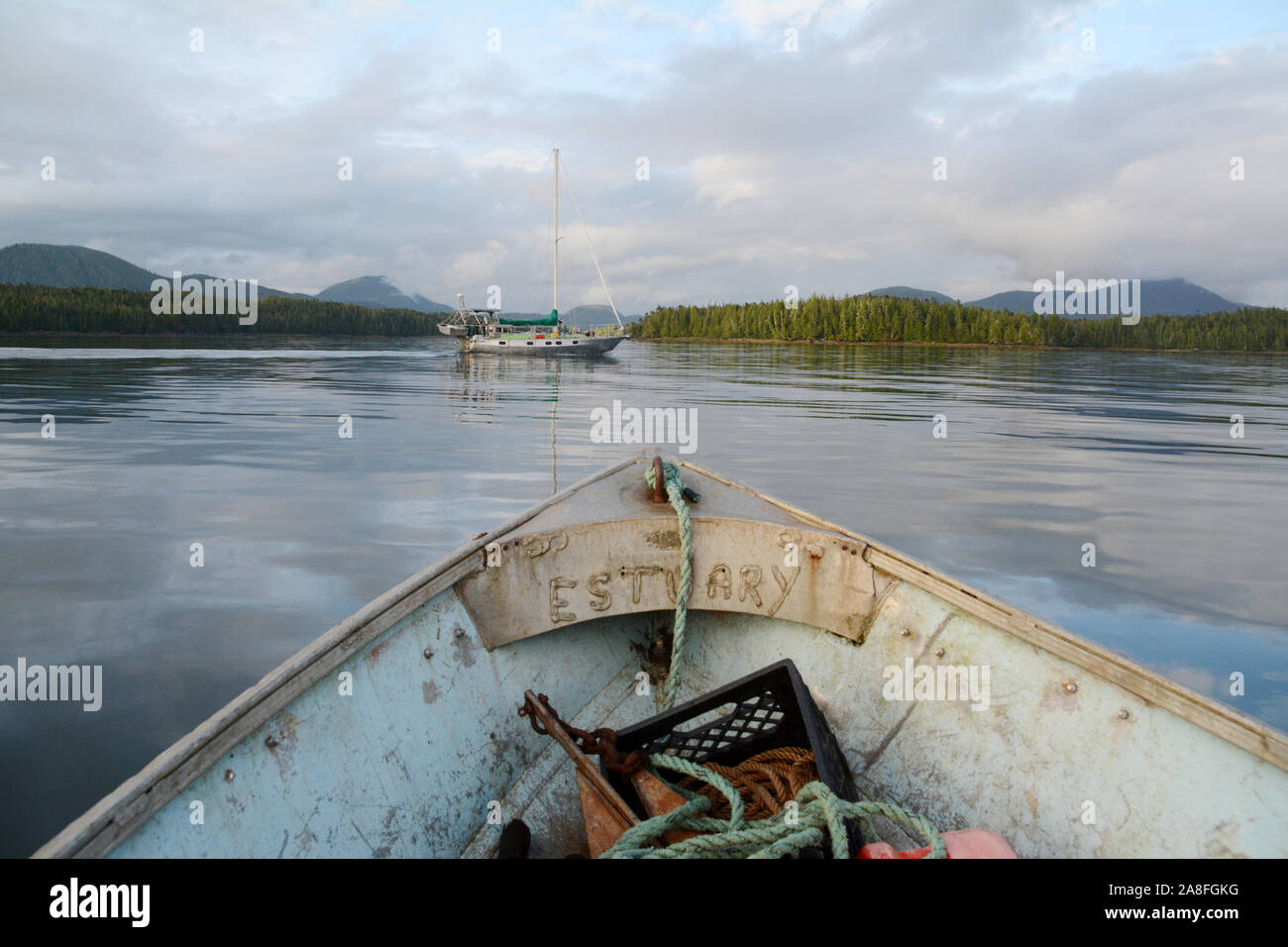 Ein kleines Motorboot fährt in Richtung einer größeren Segelboot in den Pazifischen Ozean im Great Bear Rainforest, in der Nähe von Bella Bella, British Columbia, Kanada. Stockfoto