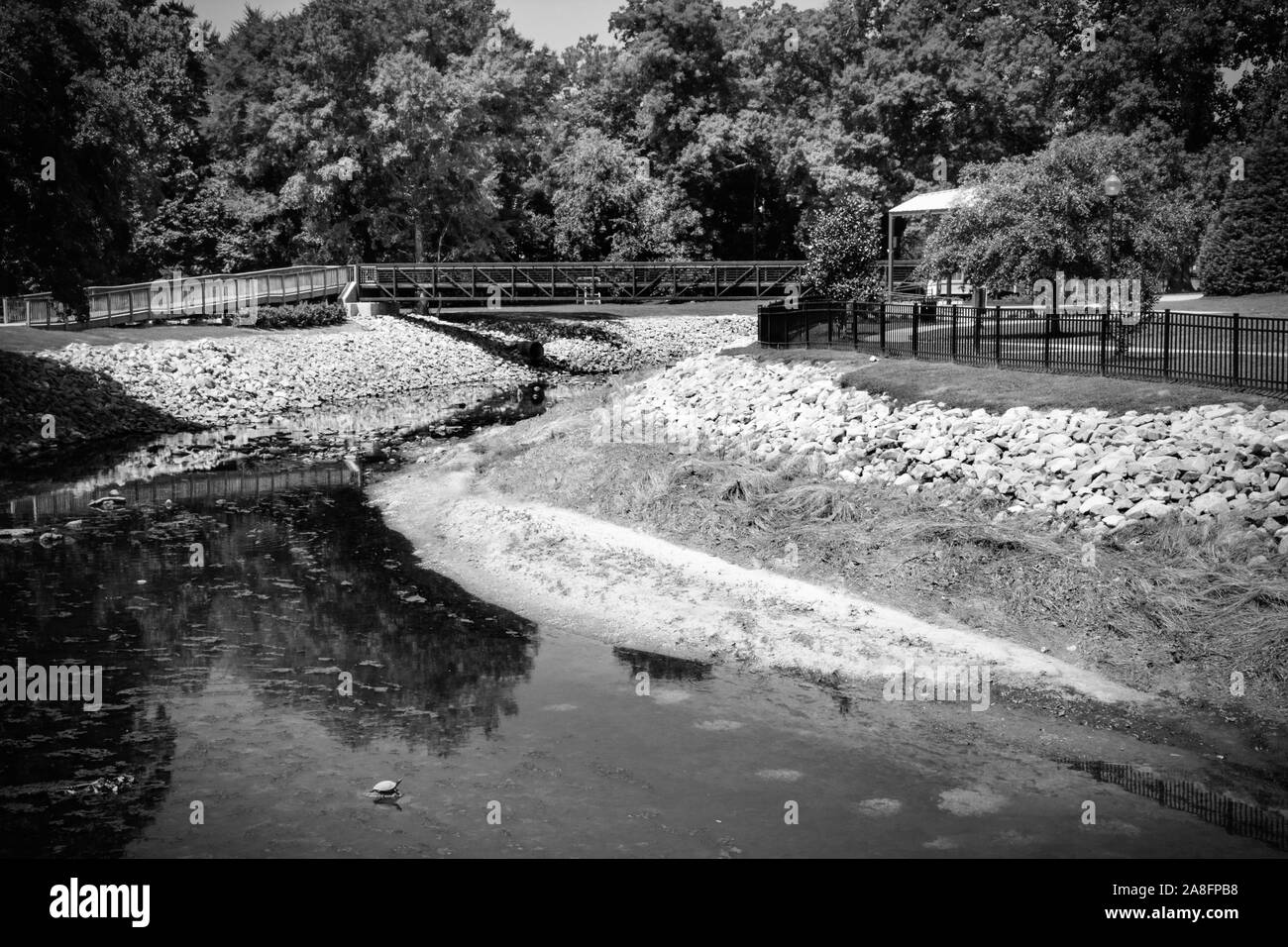 Einen schönen Blick über Gordon Creek zu einer Fußgängerbrücke und Pavillons für die Veranstaltungen im Gordon's Creek Park in Hattiesburg, MS, USA Stockfoto
