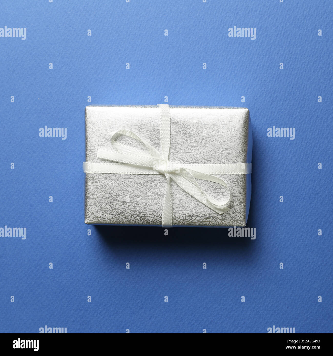 Silber Geschenkbox auf blauem Hintergrund. Weihnachten oder Geburtstag Konzept Stockfoto