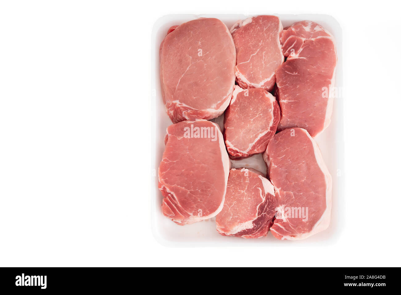 Rohes Schweinefleisch ohne Knochen Kotelett Koteletts aus weißem Kunststoff Behälter, Nahaufnahme, direkt von oben, auf weißem Hintergrund Stockfoto