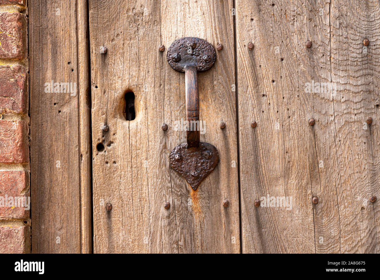 Alte äußere Tür in abgenutzt und verwittertes Holz mit rostigen Griff und der Öffnung für die Lock Stockfoto